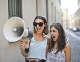 cheerful young women screaming into loudspeaker