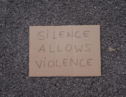 slogan silence allows violence on asphalt road; criticism