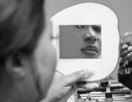 a grayscale photo of a woman looking at the mirror